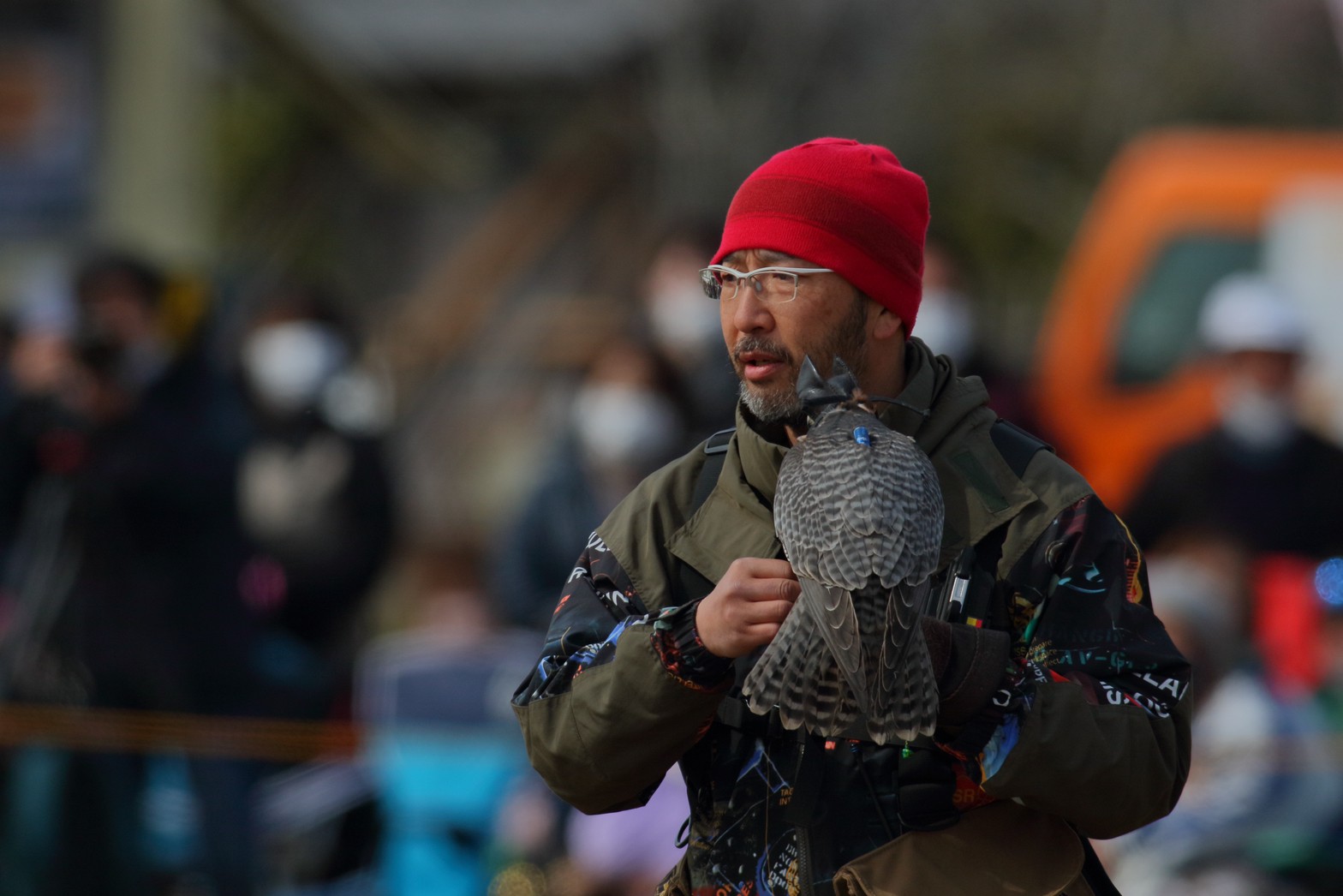 赤い帽子をかぶり、ハヤブサを腕に乗せた青山智之